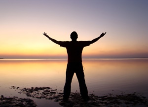 Liberdade é um dom de Deus - homem de braços abertos contemplando o pôr do sol